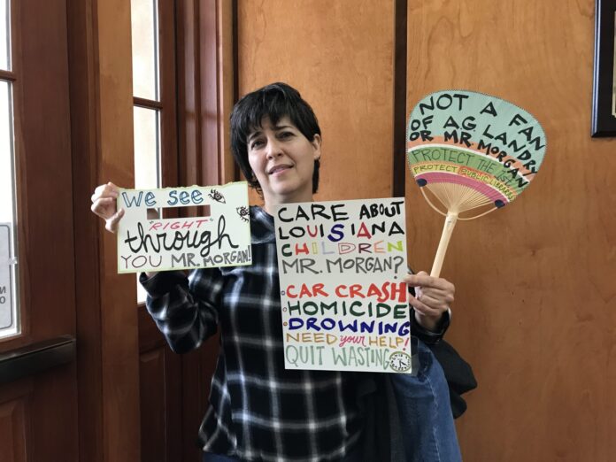 Jennifer Cooper holds up signs at the Tuesday, March 21, 2023, meeting of the Rapides Parish Library Board of Control. Attorney General Jeff Landry declined to provide an opinion on a change the board is considering to policy for its children’s section. (Photo by Frances Madeson)